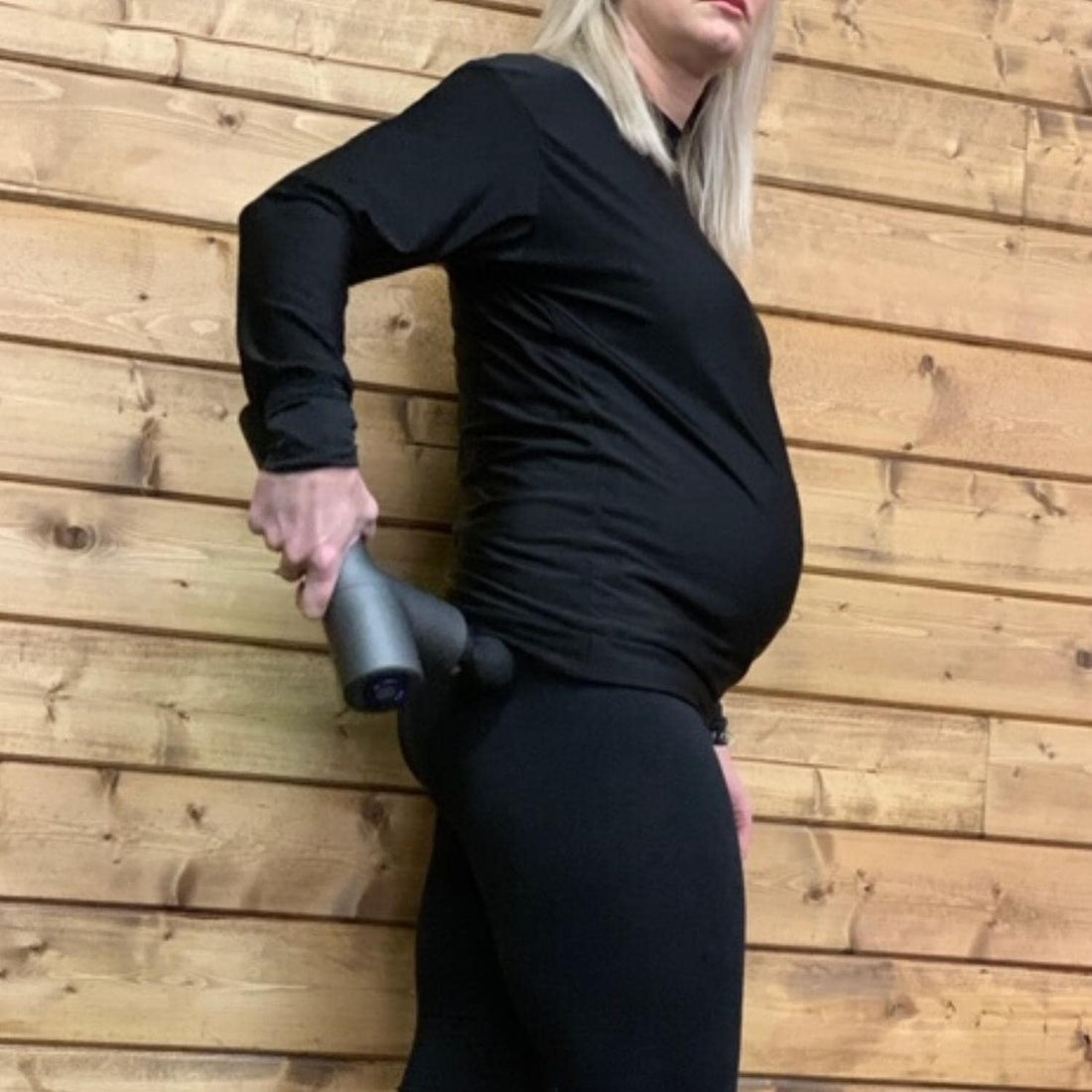 pregnant crossfit mom using percussion massager to relax image